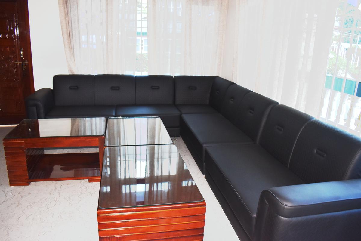 Mini bar lounge with black leather L-shaped sofa and coffee tables at Hotel Pema Lhatse