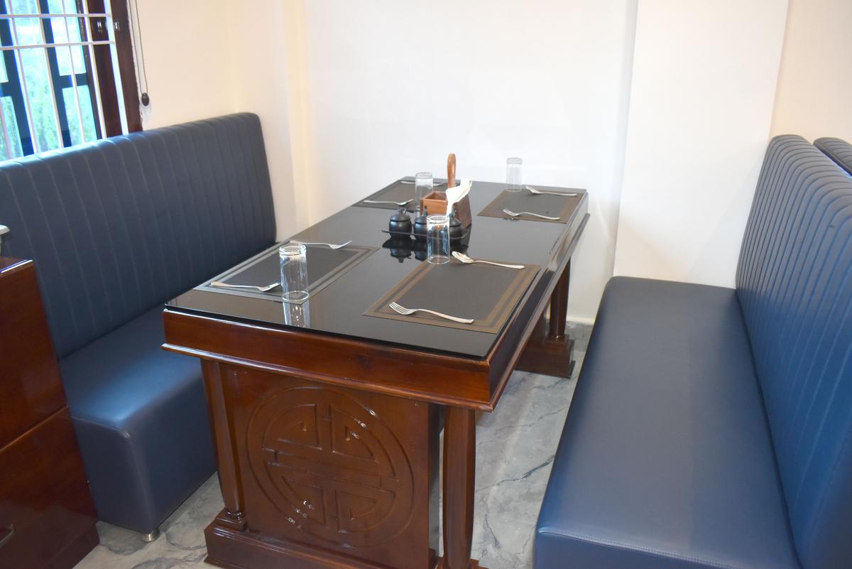 Restaurant table setting closeup with cutlery and booth seating at Hotel Pema Lhatse